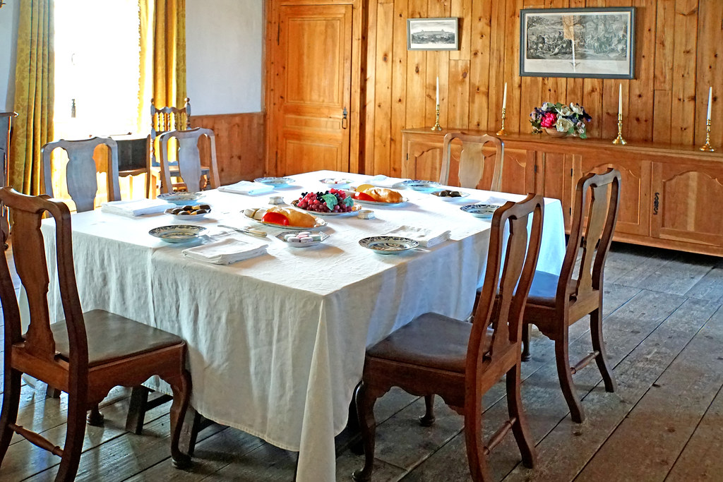 Wood-paneled dining room with a set table and period chairs